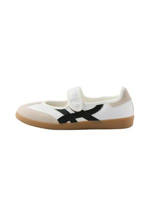 Scarpa slip-on bianca e beige con strisce nere, cinturino in velcro e suola in gomma naturale, vista di lato su sfondo bianco.