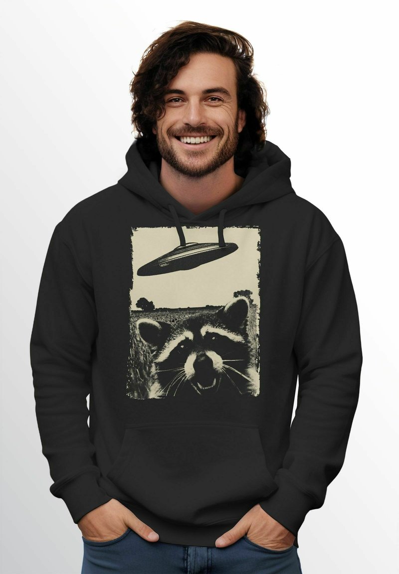 Schwarzer Kapuzenpullover mit einem in einem abgenutzten, vintage Stil gedruckten Waschbär-Graphic über einem fliegenden Untertassen-Motiv. Weicher Stoff mit lockerer Passform.