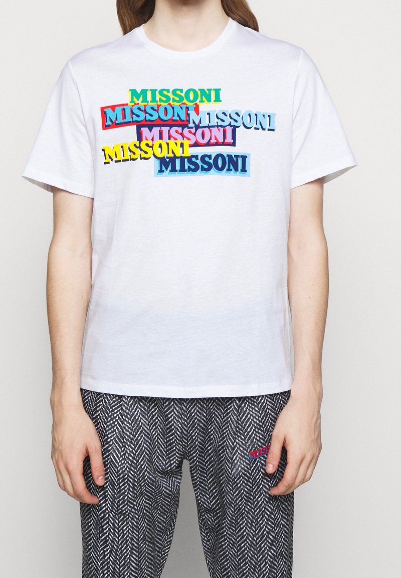 T-shirt en coton blanc avec le texte multicolore « MISSONI » en gras, dans des styles qui se chevauchent. Manches courtes et col rond.
