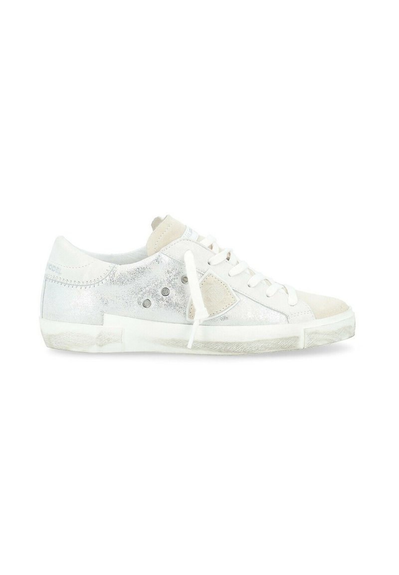 Sneaker bianco con accenti metallici argento, sovrapposizioni in suede e occhielli circolari. Lacci piatti e suola testurizzata per una migliore aderenza.
