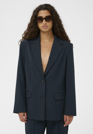 Mørkeblå blazer i struktureret stof med kløftede revers, to-knaps lukning og to frontlommer.