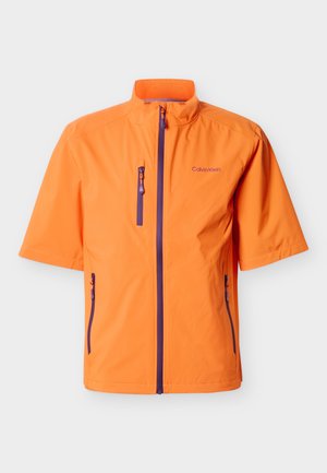 Veste zippée orange vif à manches courtes avec col montant, fermetures éclair violettes et logo Calvin Klein sur la poitrine gauche.