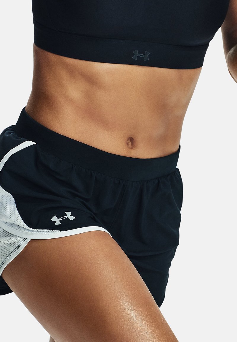 Must mustreene crop top ja mustad lühikesed püksid valgete võrgukangast aktsentidega, millel on elastne vöökoht ja Under Armouri logo pükste küljel.