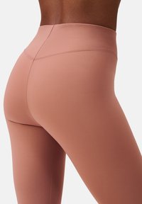 Hoge taille roze leggings gemaakt van een gladde, rekbare stof. Beschikt over subtiele naden en een aansluitend ontwerp voor comfort en bewegingsvrijheid.