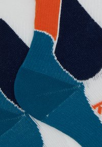 Calzini multicolori con motivo geometrico in blu navy, arancione e verde acqua. Realizzati in materiale lavorato a maglia, mostrano sezioni testurizzate e colori a contrasto.