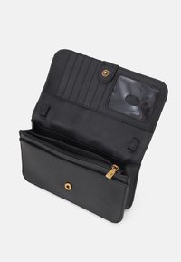 Černá kožená peněženka s zipovou kapsou, sloty na karty a průhledným oknem na ID. Obsahuje zlaté zacvakávací zapínání a kovové akcenty.