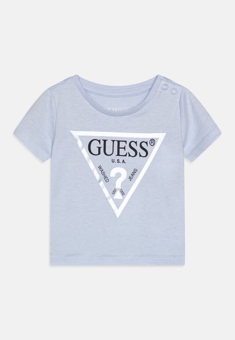 Šviesiai mėlyna trumpomis rankovėmis medvilninė marškinėlių su trikampiu juodu ir baltu "GUESS" logotipo grafiku priekyje. Papildomai turi spaudimo mygtukus ant peties.