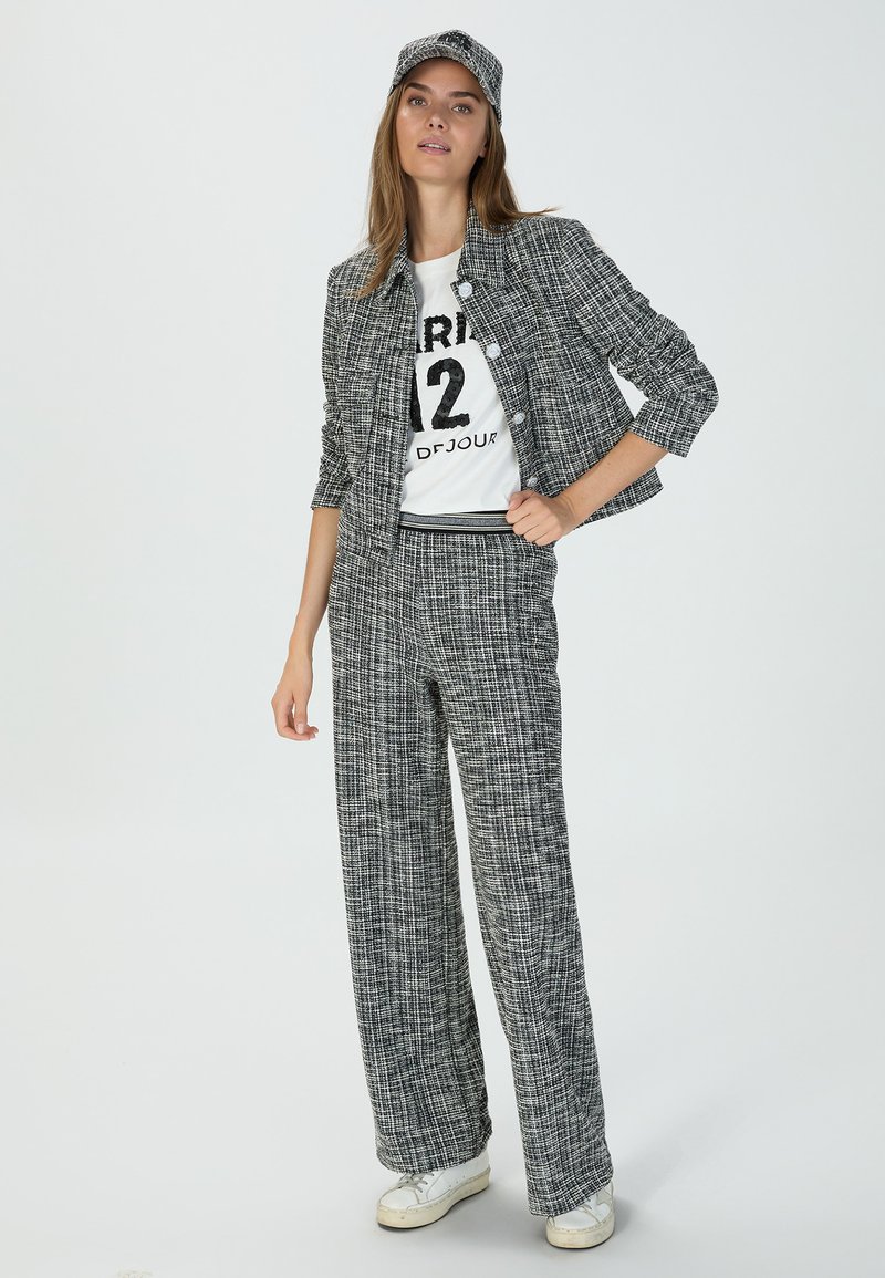 Black and white checked suit with a fitted jacket, wide-leg pants, and a cap. The jacket features buttons, and the ensemble has a casual fit.