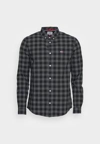 Camicia a scacchi nera e grigia con maniche lunghe, colletto e un piccolo logo sul petto. Presenta bottoni bianchi e un motivo a quadrati.