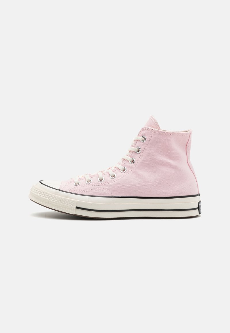 Baskets montantes en toile rose clair avec semelle en caoutchouc blanche et détail de rayure noire, vues de côté sur un fond uni.