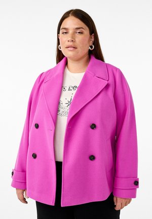 Manteau en laine rose à double boutonnage avec de grands boutons noirs et un large col, présentant des épaules structurées et une coupe légèrement oversized.