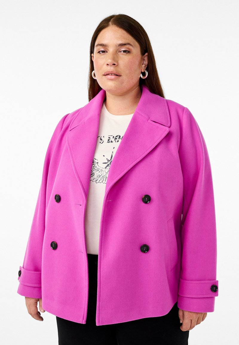 Dubbelsidig rosa ullrock med stora svarta knappar och breda slag, med strukturerade axlar och en något oversized passform.