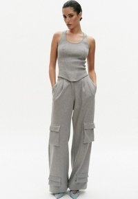 Grijze tanktop met een getailleerde silhouette, gecombineerd met losse grijze cargobroek met zakken en elastische boorden. Gladde textuur, eenvoudig ontwerp.