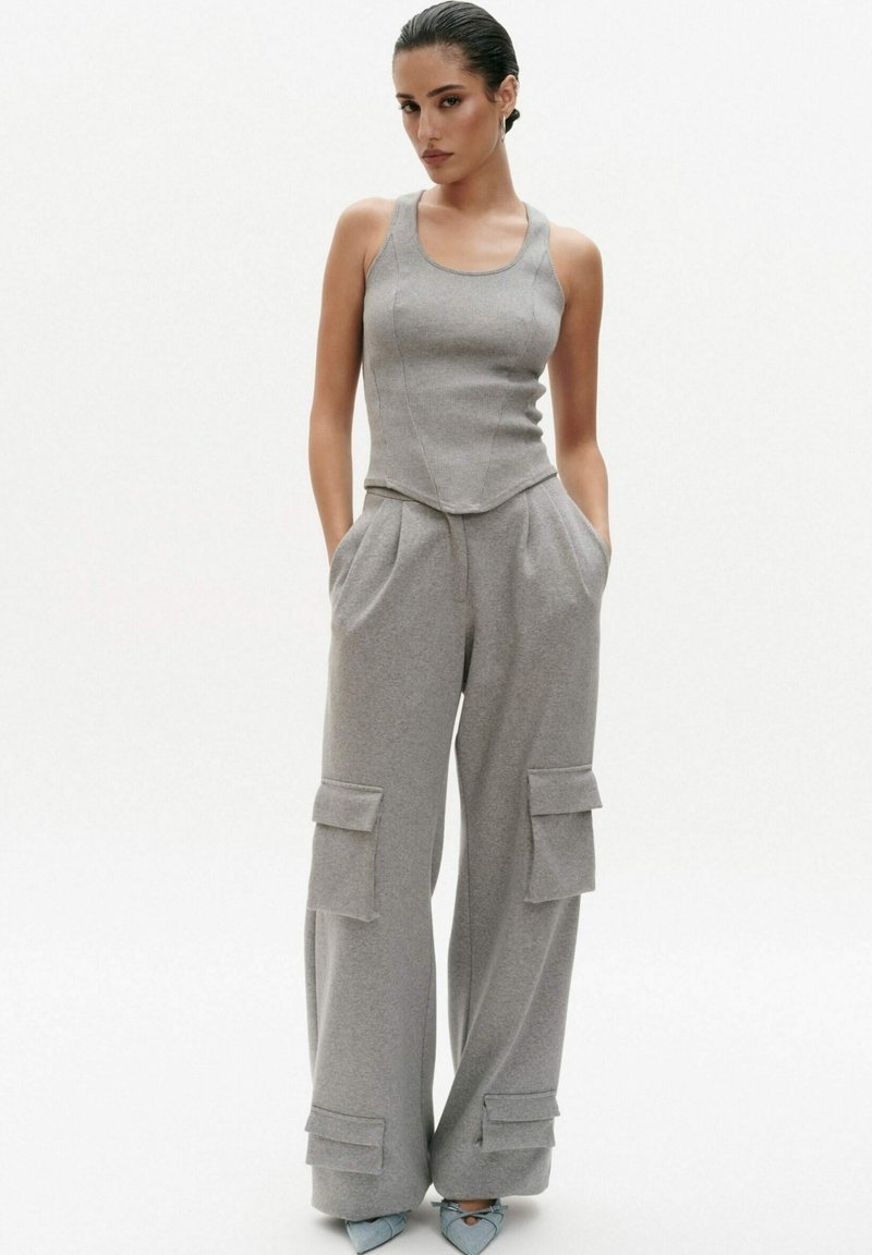 Grijze tanktop met een getailleerde silhouette, gecombineerd met losse grijze cargobroek met zakken en elastische boorden. Gladde textuur, eenvoudig ontwerp.