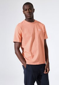 T-shirt met korte mouwen en ronde hals in koraalkleur, gemaakt van een katoenmengsel. Voorzien van een klein logo op de linkerborst en een losse pasvorm.