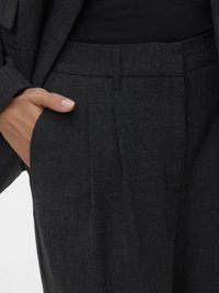 Temno sive hlače po meri z teksturirano tkanino, ki imajo raven sprednji del, stranske žepke in uglajen pas.