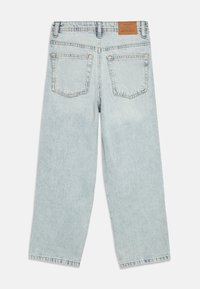 Hele sinised teksapüksid lõdva lõikega, sirge säärega, kahe tagataskuga ja nahast plaastriga vöökohal.