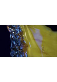 Et nærbilde av et gjennomsiktig, blankt materiale med glatte gule og blå overflater, som har intrikate teksturer og flytende former.