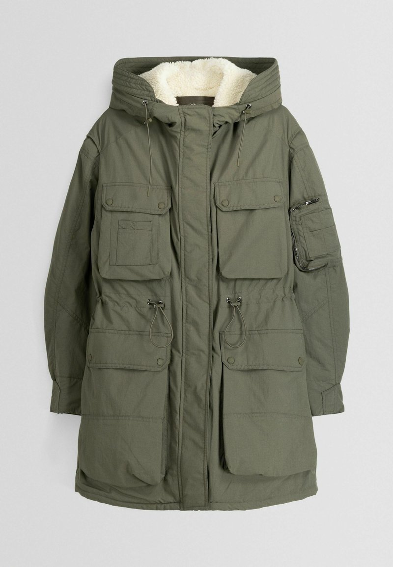 Parka olive verte avec une doublure blanche en peluche, dotée de plusieurs poches avant, de cordons de serrage réglables et d'une capuche.