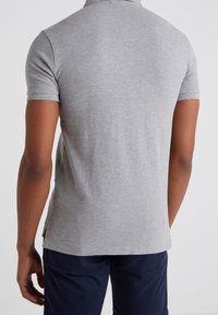 Polo shirt grigio a maniche corte realizzato in un tessuto testurizzato, con colletto e fessure laterali all'orlo per una maggiore comodità.