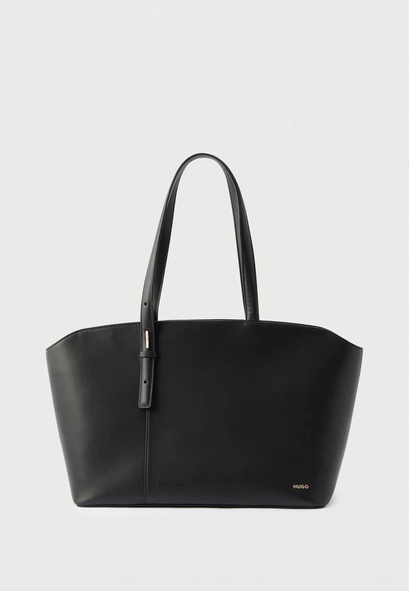 Μαύρη δερμάτινη τσάντα ώμου με δύο χειρολαβές και μικρό χρυσό λογότυπο "HUGO" στην κάτω δεξιά γωνία, σε λευκό φόντο.