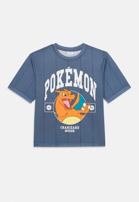 Mėlyna trumpomis rankovėmis marškinėliai su Charizard grafika, ant kurios baltais rašmenimis užrašyta "POKÉMON" ir "#0006". Šiek tiek tekstūruotas audinys, laisvas kirpimas.