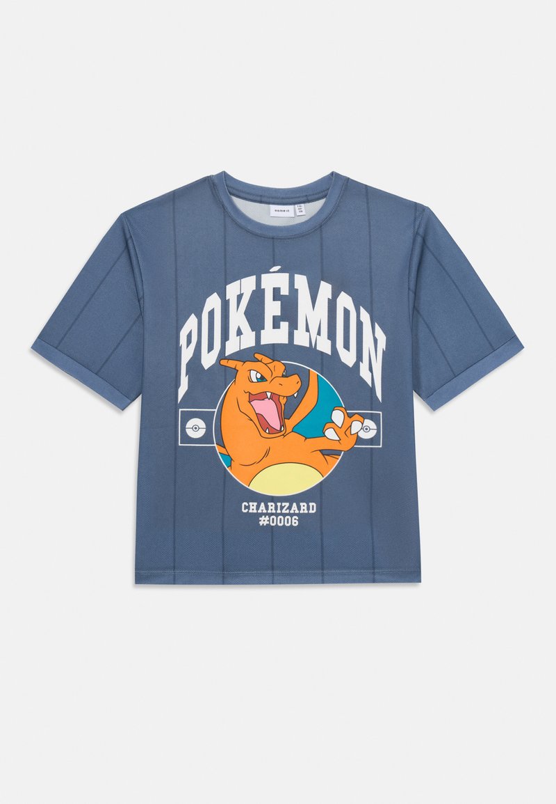 Mėlyna trumpomis rankovėmis marškinėliai su Charizard grafika, ant kurios baltais rašmenimis užrašyta "POKÉMON" ir "#0006". Šiek tiek tekstūruotas audinys, laisvas kirpimas.