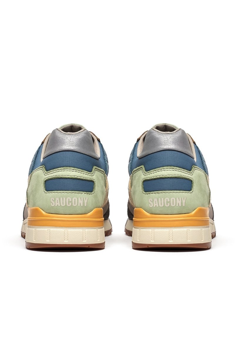 Een paar veelkleurige Saucony sneakers gezien vanaf de achterkant, met groene, blauwe, grijze, oranje en beige accenten op de zool en bovenkant.