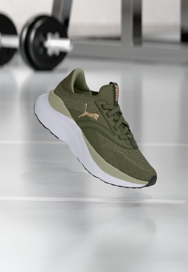 Oliwkowe buty sportowe z teksturowaną cholewką z dzianiny, kontrastującymi jasnooliwkowymi akcentami i grubą białą podeszwą. Złoty detal logo po boku.