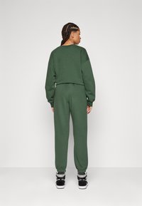 Groene katoenen blend cropped sweatshirt en joggers, met ribbed cuffs en tailleband, gecombineerd met zwarte high-top sneakers.