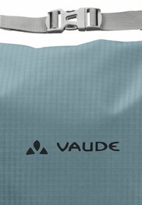 Helles, wasserfestes Blaues Bag mit einer strukturierten Oberfläche. Verfügt über einen obereren Riemen mit einer silbernen Schnalle und einem schwarzen "VAUDE"-Logo zur Markenkennzeichnung.