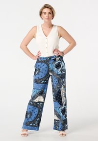 Blauwe wijde broek met een patroon van een mix van paisley- en geometrische ontwerpen. De stof is zacht en heeft een losse fit; gecombineerd met een witte textuurtop.