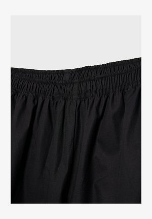 Čierna látka s nariaseným elastickým pásom, viditeľné švy, bez iných predmetov alebo osôb.