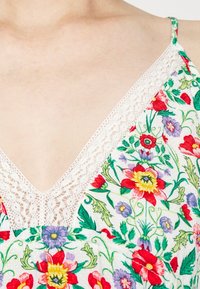 Abito floreale con un bordo in pizzo bianco lungo il décolleté a V, decorato con fiori colorati in rosso, viola e verde su uno sfondo chiaro.