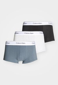 Three pairs of boxer briefs in blue, grey, and black, featuring a white waistband with "Calvin Klein" logo, made from soft fabric.