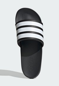 Sandale noire à semelle plate avec trois rayures blanches horizontales. Sangle et semelle texturées, avec le logo "adidas" sur la semelle intérieure.