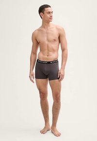 Tamnosive muške bokserice s crnim elastičnim pojasom na kojem je logo "TOM TAILOR". Mekani materijal i uski kroj.