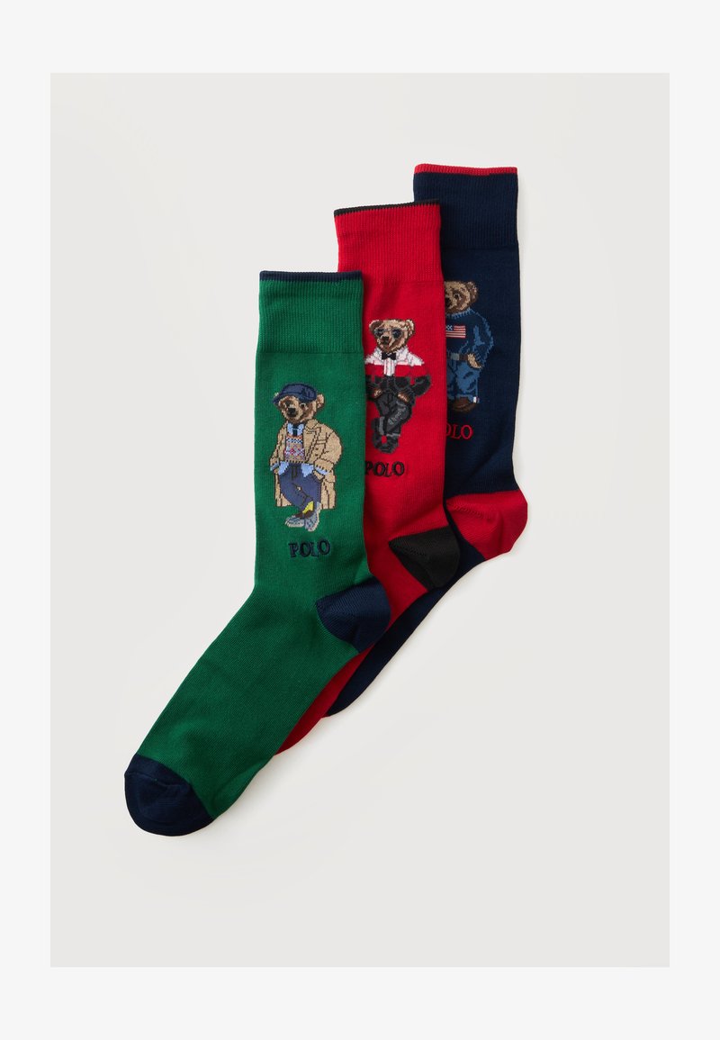 Trois chaussettes colorées en vert, rouge et bleu marine, chacune avec un ours habillé de tenues élégantes et le mot POLO en dessous.