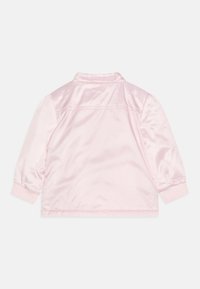 Růžová saténová bunda s hladkým povrchem, vybavená límcem, žebrovanými manžetami a jednoduchým designem. Bez viditelného kování nebo ozdob.