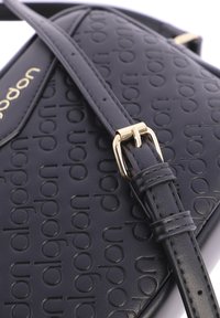 Bolso de mano sintético negro con patrón de logo en relieve, herrajes en tono dorado, correa ajustable, textura suave y forma estructurada.