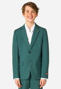 Blazer turchese con due bottoni, risvolti a punta e tasche frontali. Camicia bianca sotto. Presenta un accento arancione sul polsino con la scritta "DAILY."
