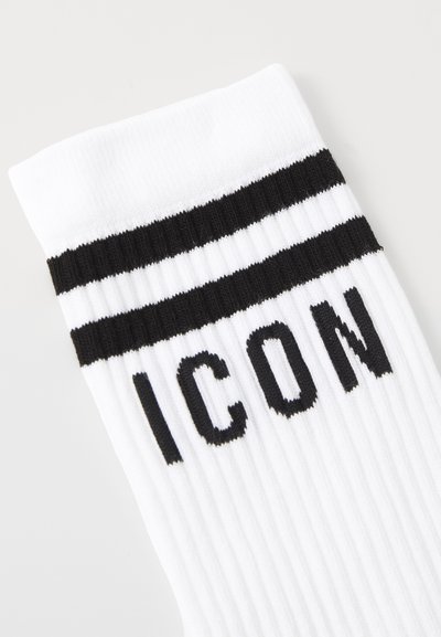 Valged puuvillased sokid, millel on sooniline tekstuur, lõpetatud kahe musta triibuga pahkluul ja sõna "ICON" julgete mustade tähtedega.