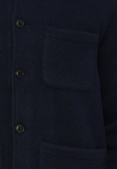 Veste chemise en mélange de laine bleu marine avec une coupe décontractée, dotée d'une poche poitrine, d'une fermeture à boutons et d'un tissu texturé. Deux poches frontales.