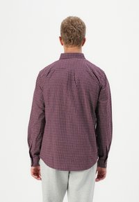 Long-sleeve shirt in maroon and white check pattern, featuring a classic collar, buttoned cuffs, and a back yoke with pleats.