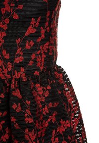 Musta mekko, jossa on punaisia kukkakuvioita, teksturoitu kangas ja levenevä helma, korostaen elegantteja suunnitteluyksityiskohtia.