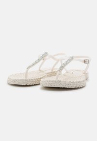 White flip-flops with a textured sole, featuring a smooth, flexible strap adorned with clear rhinestones for decoration.