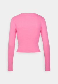 Long-sleeve, cropped top in solid pink cotton. Features a round neckline and fitted sleeves with a smooth, soft texture.