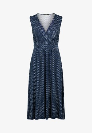 Ujjatlan tengerészkék ruha fehér és világoskék cseppmintákkal, V-nyakú, átkötős felsőrész, és derékban húzott, térd alá érő szoknya.