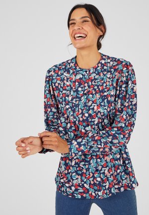 Blusa fluida a fiori in marina, con accenti rosa e teal, maniche arricciate e scollatura rotonda con dettagli a bottoni.