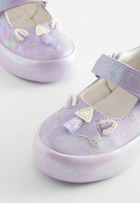 Chaussures pour enfants holographiques violettes avec un bout rond, une semelle épaisse, et des embellissements décoratifs brodés comme des oreilles et un gland.